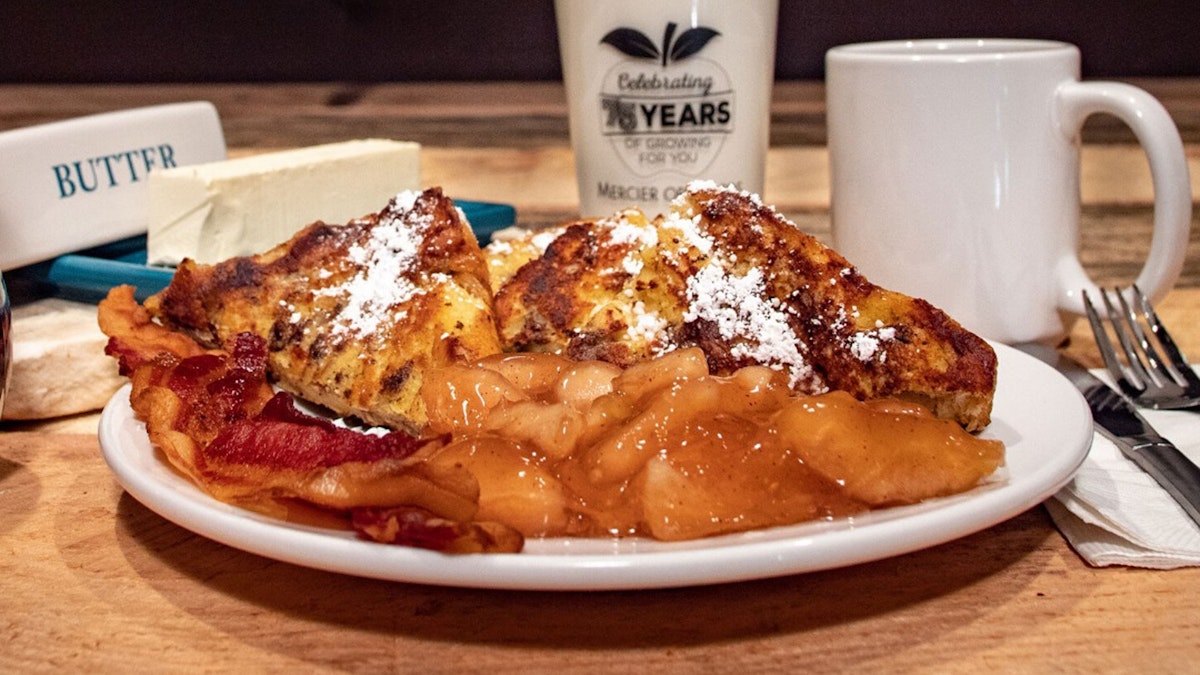 a plate full of french toast, bacon, and apples served with a cup of coffee at Mercier in Blue Ridge, GA